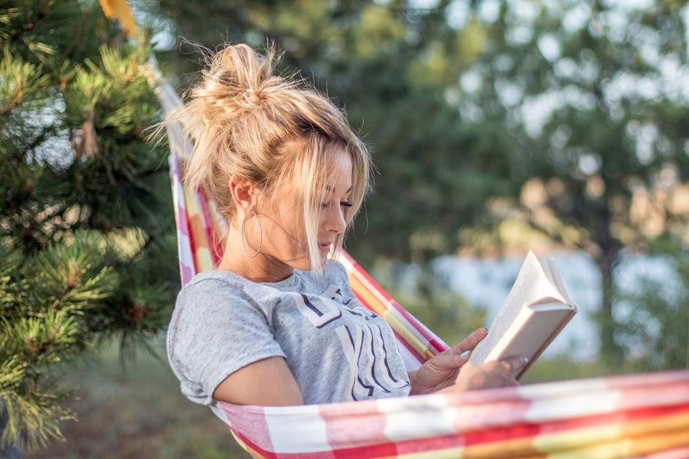 Woman reading in hammock by lake